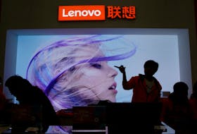 An employee gestures next to a Lenovo logo at Lenovo Tech World in Beijing, China, Nov. 15, 2019.
