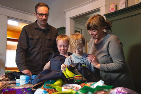 Ian Marquette, far left, and Lola Brown, far right, have begun helping food-insecure families in with children in Truro Elementary through the Truro Elementary Backpack Program, an eight-week pilot project which sends kids home with backpacks full of food to keep them from going hungry over the weekend. Helping them prepare backpacks are two of their children, Carmelo Marquette, left, and Rocco Marquette, right. Nick Gaines