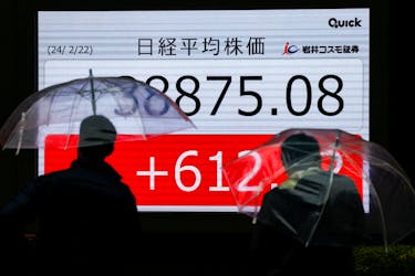 People stand in front of electronic screens displaying Japan's Nikkei share average outside a brokerage in Tokyo, Japan February 22, 2024. 