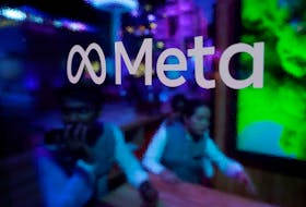 People are seen behind a logo of Meta Platforms, during a conference in Mumbai, India, September 20, 2023.