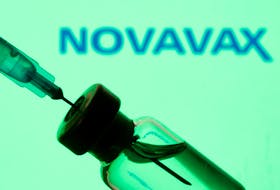 A vial and sryinge are seen in front of a displayed Novavax logo in this illustration taken January 11, 2021.