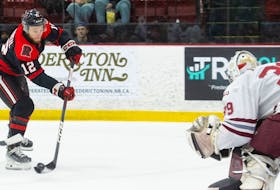 UNB Reds forward Benjamin Corbeil fires a shot on Saint Mary's Huskies goalie Jeremy Helvig during Game 1 of their AUS hockey semifinal Friday in Fredericton - UNB Athletics
