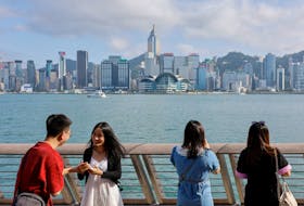 Mainland Chinese tourists take photo of the skyline of buildings at Tsim Sha Tsui, in Hong Kong, China May 2, 2023.
