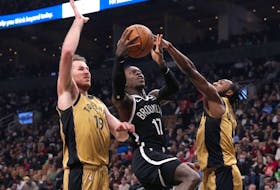 Brooklyn Nets' Dennis Schroder (centre) shoots between Toronto Raptors' Jakob Poeltl (left) and Immanuel Quickley in Toronto on Thursday, February 22, 2024. 