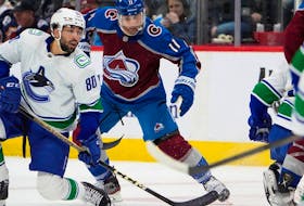 Arshdeep Bains, left, making his Canucks debut, jostles for position with Colorado Avalanche centre Andrew Cogliano in the first period on Tuesday in Denver