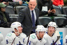 Canucks head coach Rick Tocchet talks with J.T. Miller (left), Pius Suter and right wing Brock Boeser.