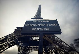 A sign reading "Due to a strike, the Eiffel Tower is closed. We apoligize" hangs in front of the Eiffel Tower in Paris, France, February 19, 2024. Picture taken through glass.
