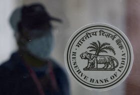 A man walks behind the Reserve Bank of India (RBI) logo inside its headquarters in Mumbai, India, April 8, 2022.