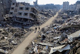 Palestinians walk past destroyed houses, amid the ongoing conflict between Israel and Hamas, in Jabalia refugee camp, in the northern Gaza Strip February 22, 2024.