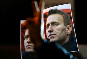 A person gestures in front of portraits of Russian opposition leader Alexei Navalny as people attend a protest and vigil held in front of the Russian embassy following the death of Navalny, in Kappara, Malta, February 19, 2024.