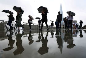 Commuters carry umbrellas while crossing London Bridge in London, Britain August 2, 2023.