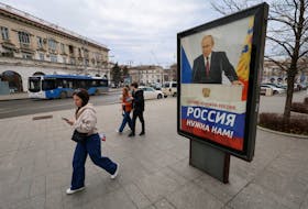 Pedestrians walk past a poster displayed in support of Russia's President Vladimir Putin in a street in the Black Sea port of Sevastopol, Crimea, February 14, 2024. A slogan on the poster reads: "Russia is not needed for the West, Russia is needed for us!