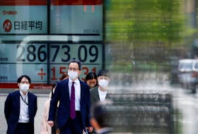 Passersby walk past an electric board displaying Japan's Nikkei share average outside a brokerage in Tokyo, Japan April 18, 2023. 
