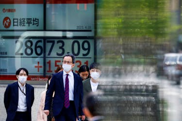 Passersby walk past an electric board displaying Japan's Nikkei share average outside a brokerage in Tokyo, Japan April 18, 2023. 