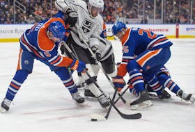 Cody Ceci (5) and Darnell Nurse (25) of the Edmonton Oilers battle for possession against Pierre-Luc Dubois (80) of the Los Angeles Kings at Rogers Place in Edmonton on Feb. 26, 2024.