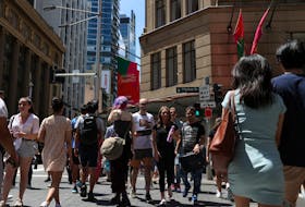 People cross a busy street under holiday decorations in the city centre of Sydney, Australia, December 17, 2020. 