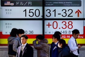 Passersby walk past a screen displaying the Japanese yen exchange rate against the U.S. dollar outside a brokerage in Tokyo, Japan February 16, 2024. 