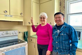 Harvey Ngo, right, poses with Montague resident Blanche Moyaert beside the kitchen cupboards he painted for her in December. Ngo has been using social media to encourage Islanders unable to afford painters to contact him for free interior painting assistance. Thinh Nguyen • The Guardian
