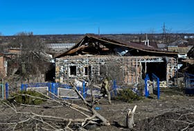 A police officer walks past a damaged house in the frontline town of Orikhiv, amid Russia's attack on Ukraine, in Zaporizhzhia region, Ukraine February 28, 2024.