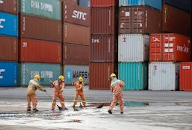 Workers clean the ground in front of containers at Tien Sa port in Da Nang city, Vietnam, March 6, 2020.
