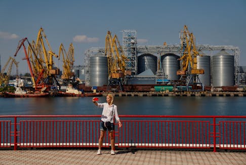 A woman takes a selfie with a grain terminal in a background in the sea port in Odesa after restarting grain export, as Russia's attack on Ukraine continues, Ukraine August 19, 2022.