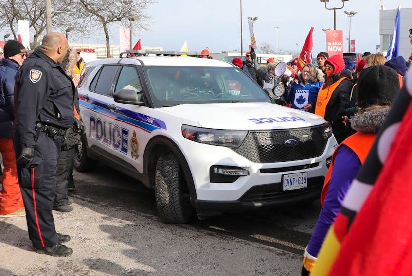 An Ottawa police cruiser surrounded by a crowd as PSAC demonstrators block traffic on Star Top Road Wednesday. 