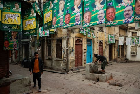 A man walks along a street filled with campaign posters a day ahead of the general election, at the Walled City in Lahore, Pakistan February 7, 2024.