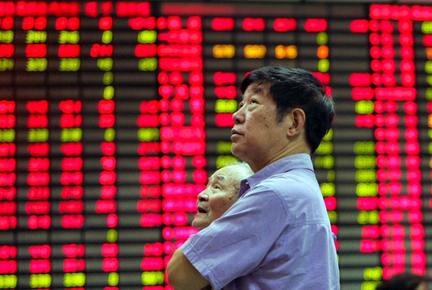 A man stands in front of an electronic stock board in the stock market of Shanghai June 19, 2006.