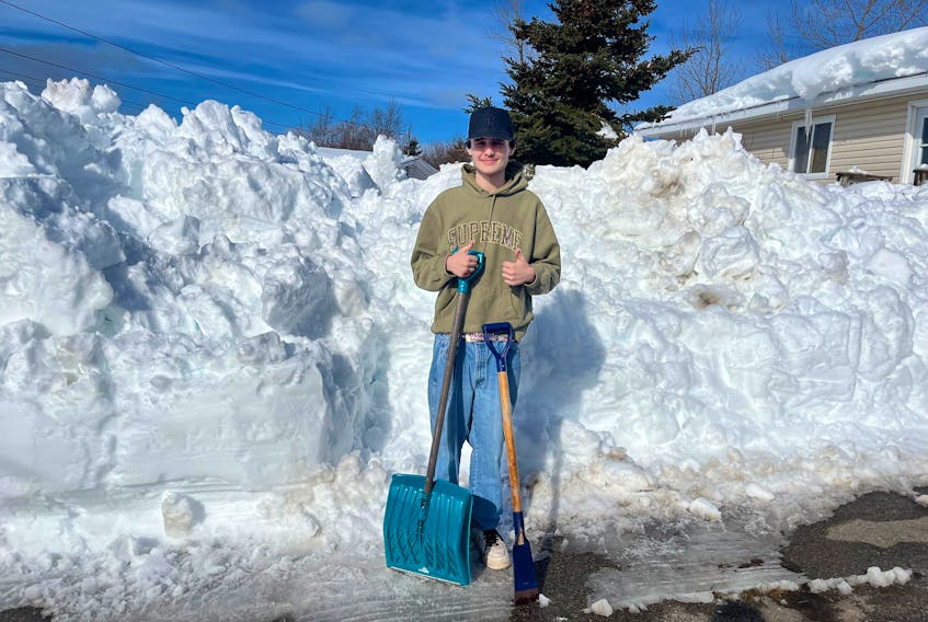 Aiden Murphy, 18, stands beside a snowbank in Sydney near his home with his shovel and ice pick in hand. From Saturday to Thursday, Murphy shovelled out seniors and people with disabilities in his neighbourhood to ensure medical responders had access if needed. CONTRIBUTED