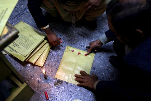 Workers seal election papers with wax at a polling station in a school during the general election, in Islamabad, Pakistan February 8, 2024.