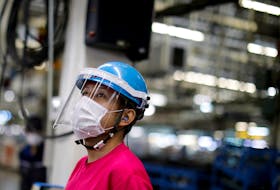 An employee wearing a protective face mask and face guard works on the automobile assembly line as the maker ramps up car production with new security and health measures as a step to resume full operations, during the outbreak of the coronavirus disease (COVID-19), at Kawasaki factory of Mitsubishi Fuso Truck and Bus Corp., owned by Germany-based Daimler AG, in Kawasaki, south of Tokyo, Japan May 18, 2020. 