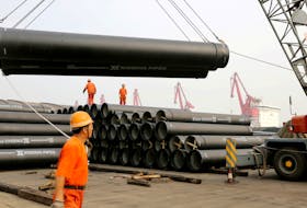 Workers direct a crane lifting ductile iron pipes for export at a port in Lianyungang, Jiangsu province, China June 30, 2019.