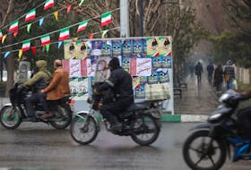 Iranians ride on a motorcycle past campaign posters for the parliamentary election during the last day of election campaigning in Tehran, Iran, February 28, 2024. Majid Asgaripour/WANA (West Asia News Agency) via REUTERS