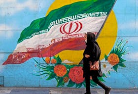 A woman walks past a mural in the Iranian capital Tehran.