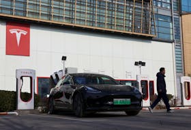 A man walks near a Tesla car at a charging station outside a store of the electric vehicle (EV) maker in Beijing, China January 4, 2024.