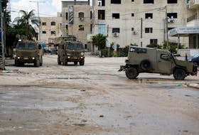 Military vehicles stand on a street during an Israeli raid at Tulkarm, in the Israeli-occupied West Bank, February 18, 2024.