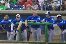 Toronto Blue Jays’ Joey Votto, centr,e stands in the dugout with teammates.