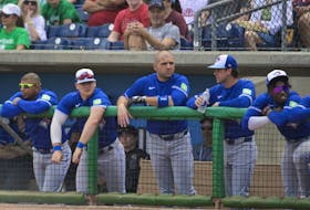 Toronto Blue Jays’ Joey Votto, centr,e stands in the dugout with teammates.