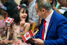 A father and his daughter celebrate after being sworn in as Canadian citizens in Windsor, Ont., in 2020.