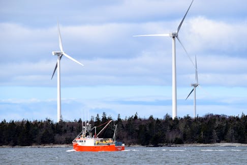 A lobster fishing boat steams out of Pubnico Harbour past the Pubnico Point wind farm. Kathy Johnson photo