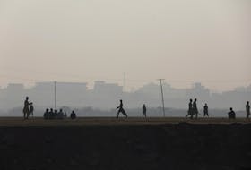 Children are silhouetted as they play cricket amid smog, as air pollution levels rise in Karachi, Pakistan, November 10, 2023.