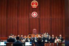 Hong Kong security chief Chris Tang poses for photos with lawmakers as they hold drafts of the Safeguarding National Security Bill, also referred to as Basic Law Article 23, before the second reading at Hong Kong’s Legislative Council, in Hong Kong, China March 19, 2024.