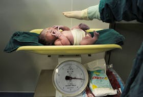A newborn baby is weighed after it was born at a hospital in Hefei, Anhui province October 31, 2011.