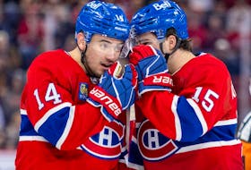 Canadiens Nick Suzuki, left, and Alex Newhook shield their mouths while discussing strategy before a faceoff against the Buffalo Sabres in Montreal on Feb. 21, 2024. Suzuki won 53.6 per cent of his draws this season — a big jump from 47.3 per cent last season.