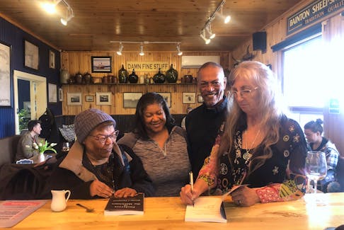 Author Brenda Thompson, right, signs copies of her book, Enslavers of the Maritimes, after a book launch at the Mad Hatter Wine Bar in Annapolis Royal on March 9. From left are Juanita Peters, her daughter, also Juanita Peters, and Richard (Buck) Stevens. The younger Juanita Peters is an activist, actor, and the executive director of the Africville Museum.   
Lawrence Powell • Special to the Annapolis Valley Register