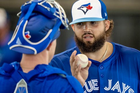 Blue Jays' Alek Manoah talks to one of the team's catchers in camp about his pitches following a throwing session. 