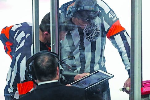 NHL officials take time out from a Flames-Canadiens game to review a play on a tablet. 