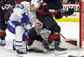 Toronto Maple Leafs' Pontus Holmberg and Carolina Hurricanes goaltender Frederik Andersen battle for control of the puck.