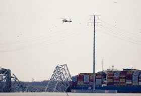 A helicopter flies over the Dali cargo vessel which crashed into the Francis Scott Key Bridge causing it to collapse, in Baltimore, Maryland, U.S., March 26, 2024.