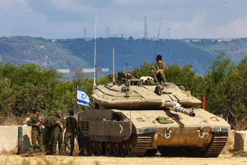 Israeli soldiers stand near a tank, near Israel's border with Lebanon in northern Israel, on Oct. 16. REUTERS/Lisi Niesner